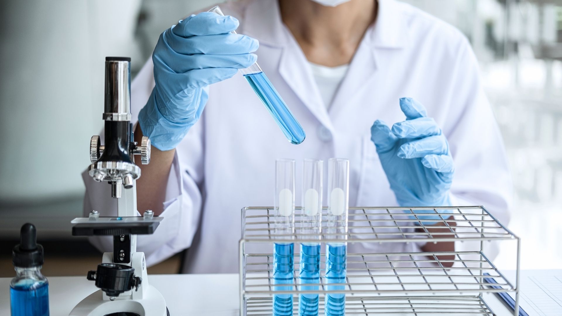 pracownik laboratorium wkłada wypełnione  probówki do stojaka